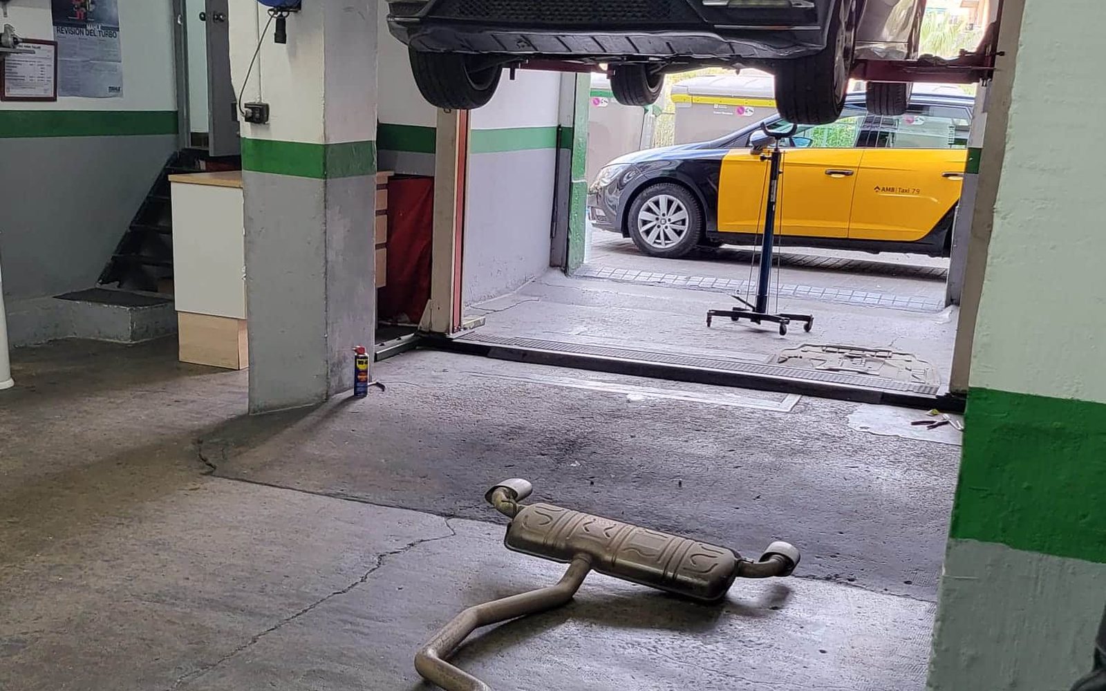 Línea de escape con el filtro de partículas desmontada bajo un coche en el elevador de Taller Garrido