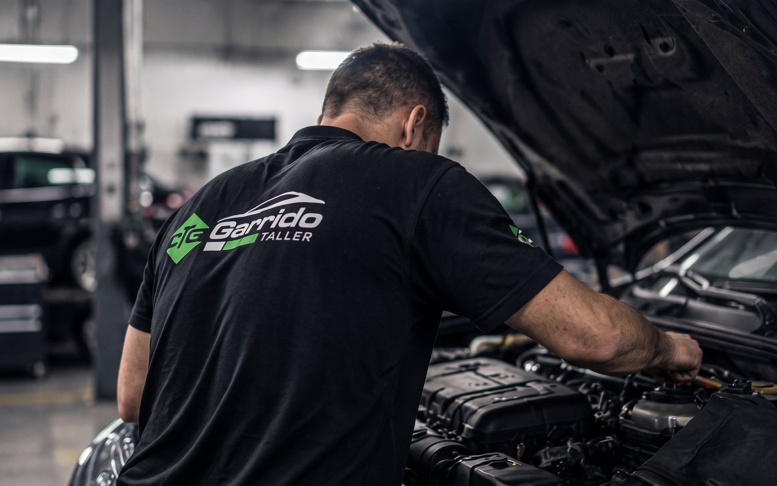 Mecánico de Taller Garrido revisando el motor de un coche con el capó abierto